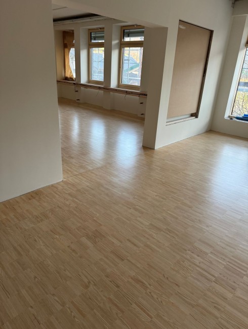Heller Raum mit großen Fenstern und Holzboden
